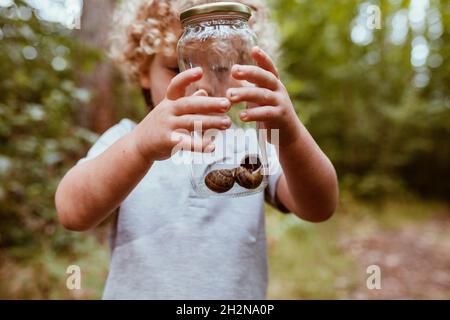 Boy holding glass jar with snails Stock Photo