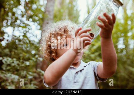 Boy looking at snails in glass jar Stock Photo