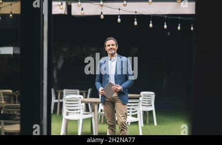 Thoughtful mature businessman holding digital tablet at hotel Stock Photo