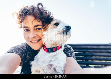 Smiling woman with Jack Russell Terrier taking selfie during sunny day Stock Photo