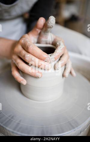 Young female potter making shape on pottery wheel in workshop Stock Photo