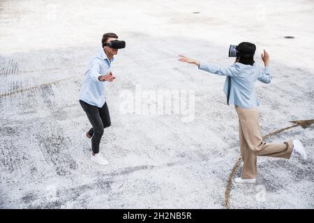 Male and female colleagues using virtual reality headset on rooftop Stock Photo