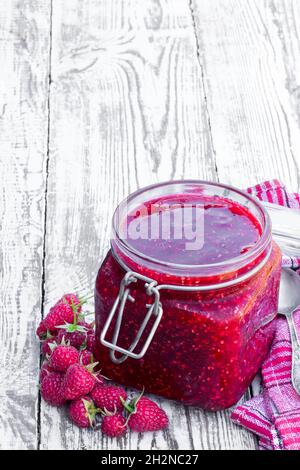 Raspberry  jam in glass jar on white wooden table Stock Photo
