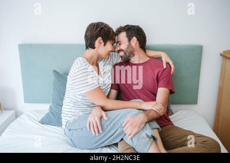 Romantic couple sitting together on bed at home Stock Photo