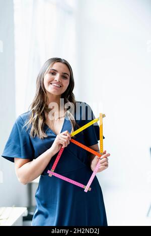 Female business professional with house shape folding ruler in office Stock Photo