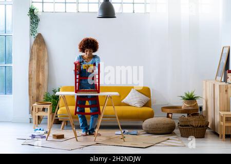 Woman with electric screwdriver using smart phone on table Stock Photo