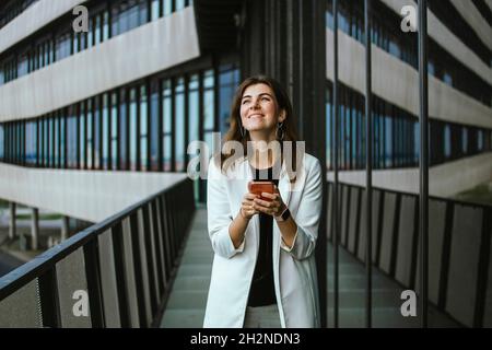 Smiling female professional text messaging through mobile phone Stock Photo