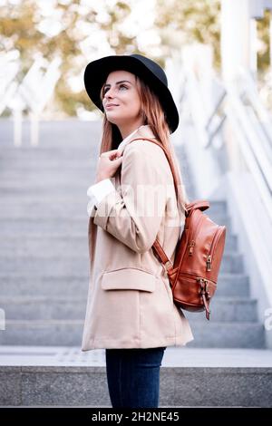 Young woman with hat and backpack standing on steps Stock Photo