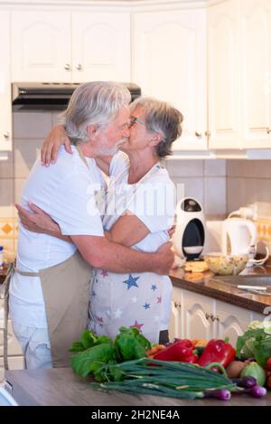 Senior couple hugging each other in kitchen at home Stock Photo