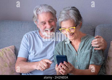 Smiling bearded man pointing at mobile phone while sitting by woman in living room Stock Photo