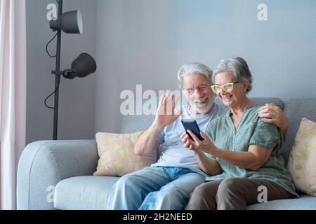 Smiling senior man waving during video call by woman at home Stock Photo