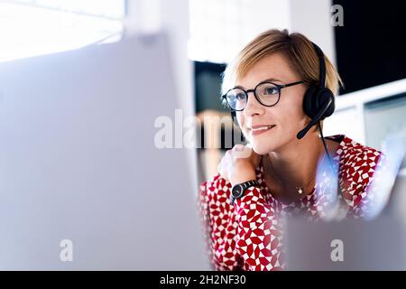 Smiling female customer service representative wearing headphones in office Stock Photo