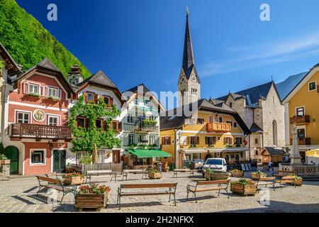 Bench and houses on footpath in town during sunny day Stock Photo