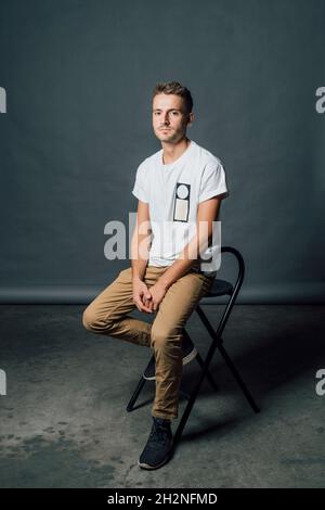 Young man sitting on chair in studio Stock Photo