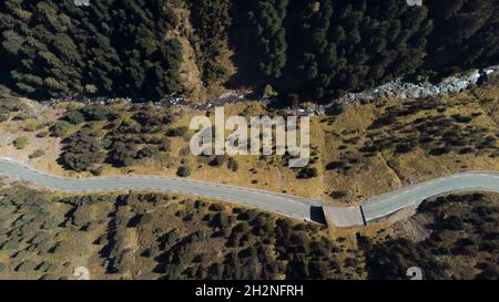 Aerial view of winding road stretching along mountain river Stock Photo