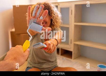 Mature man painting female friends hand with paint roller at home Stock Photo