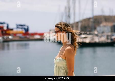 Smiling woman with brown hair wearing sunglasses on sunny day Stock Photo