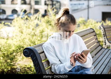 Girl using smart phone while sitting on bench Stock Photo