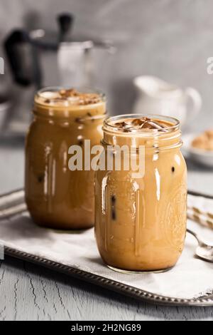 Two Mason Jars Filled with Iced Coffee with Milk or Cream and Straws Stock Photo