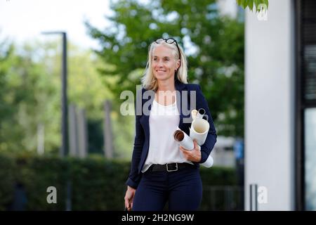 Mature businesswoman looking away while carrying blueprints Stock Photo