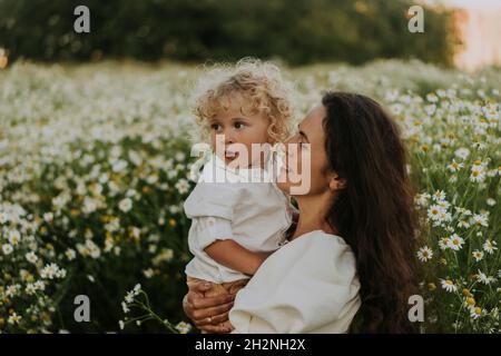 Smiling woman carrying blond baby boy at field Stock Photo