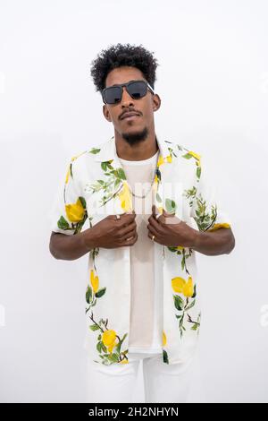 Vertical shot of a young Afro-American male in a floral shirt and sunglasses posing Stock Photo