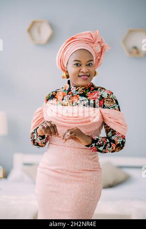 Beautiful emotional smiling woman with bright makeup against light studio  background. Studio shot of female African model in ethnic pink dress and  turban looking at camera and smiling Stock Photo - Alamy