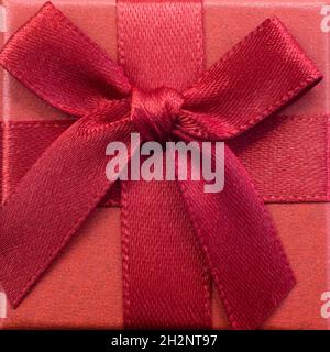 Closed red gift box with silk ribbon bow on bright pink background close up Stock Photo