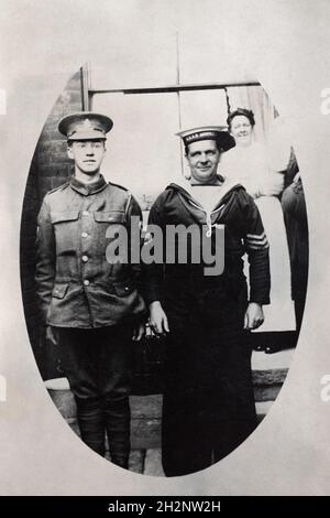 A First World War era portrait of a British army soldier, a Private in the Royal Army Medical Corps (RAMC), and an Australian salior, a Visual Signalman 3rd class with 3 long service & good conduct strips. The sailor is from the ship HMAS Australia (active 1911-1921) Australias only capital ship. A woman stands in the background looking on. Possiblly a family. Stock Photo