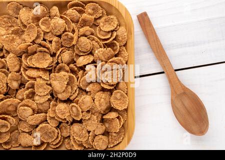 Natural multi-grain flakes in a bamboo plate with a wooden spoon on the ba, close-up, top view. Stock Photo