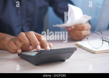 Close up of man hand using calculator and holding bills  Stock Photo