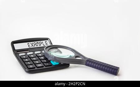 The word EXAMPLE is written on the display of a calculator and on a white background next to a magnifying glass, business concept Stock Photo