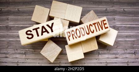 Conceptual image. Text STAY PRODUCTIVE business success concept on wooden blocks and brown table. Stock Photo