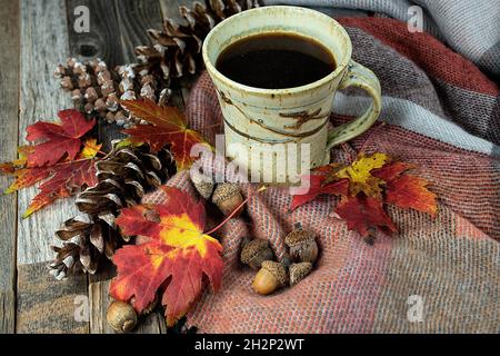 Mug of black coffee on a warm blanket with acorns, pine cones and autumn leaves Stock Photo