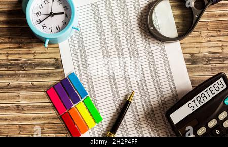 STRATEGY text on the calculator display next to documents, clock, magnifying glass and stickers. Stock Photo