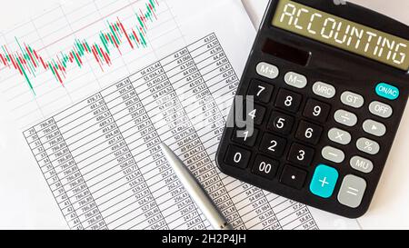 Text on accounting calculator, pen and charts with reports on a white background. Business and finance concept Stock Photo
