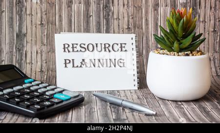 Resource planning text on the calendar, as well as a calculator, cactus and pen lie on a wooden table. Stock Photo