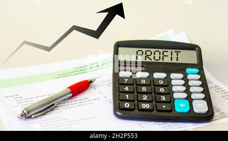 Calculator with the word profit on display, growth graph, pen and reports on a white background Stock Photo