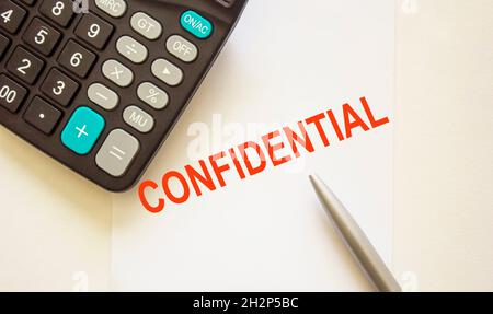 The word Privacy is written on a white sheet with a pen, next to a calculator. Stock Photo