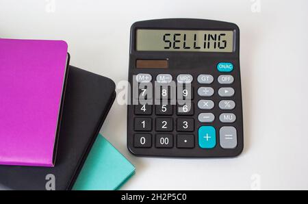 Selling text on calculator and white background, next to colored notepads Stock Photo