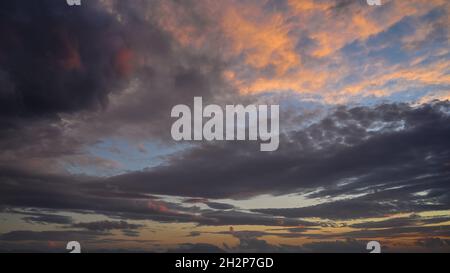 Cumulus sunset clouds, sun setting down after rainy day. Stock Photo