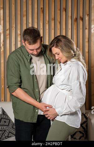 Happy couple looks tenderly at belly of pregnant woman Stock Photo