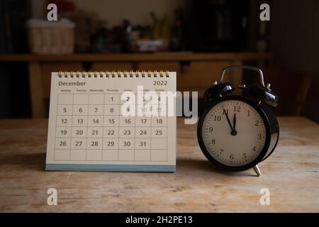 December 2022 calendar and black vintage clock on wooden table Stock Photo