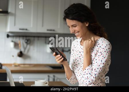Happy overjoyed woman with smartphone getting unbelievable good news Stock Photo