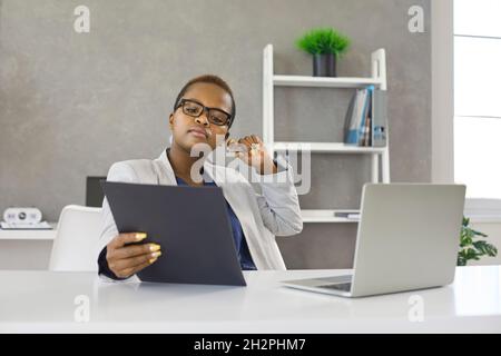 Serious female employee checks financial report, project statistics or reads correspondence. Stock Photo