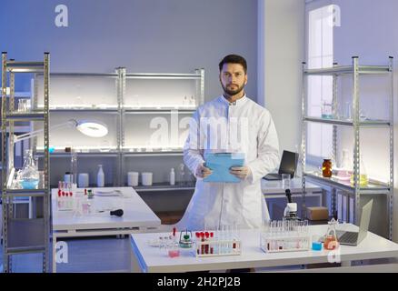 Portrait of a serious young scientist in a lab coat standing in a modern laboratory Stock Photo