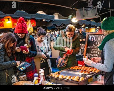 ALFRESCO FAST FOOD CHRISTMAS WINTER FRIENDS GIRLS TOGETHER BUYING SHARING STREET TAKEAWAY street food stalls with group of young women & purses paying in Covent Garden Piazza London UK Stock Photo