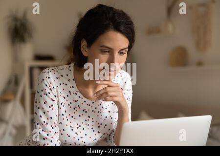 Focused smiling woman using laptop for video conference call Stock Photo