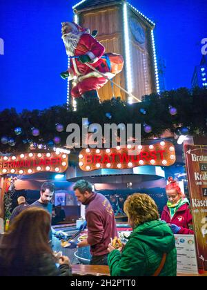 SOUTHBANK OUTDOOR TAKEAWAY GERMAN CHRISTMAS MARKET Food Stall German Christmas market food stall with skiing Father Christmas illuminated at night South Bank London UK Stock Photo