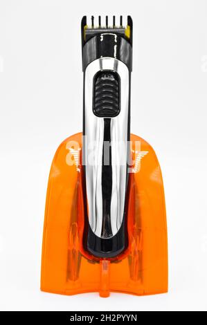 Cordless and chrome electric shaver and orange charger, charged hair clipper isolated on white background Stock Photo